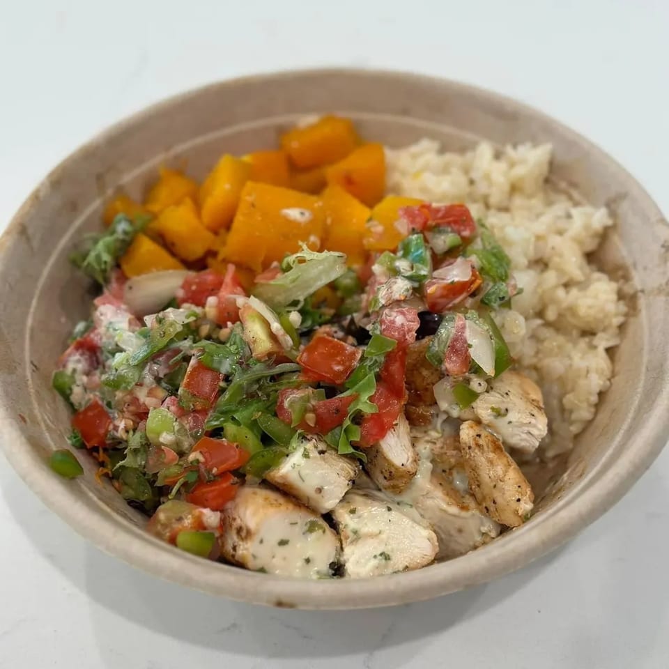 A bowl of Poppy's Place grilled chicken, rice, diced mango, and fresh salsa.