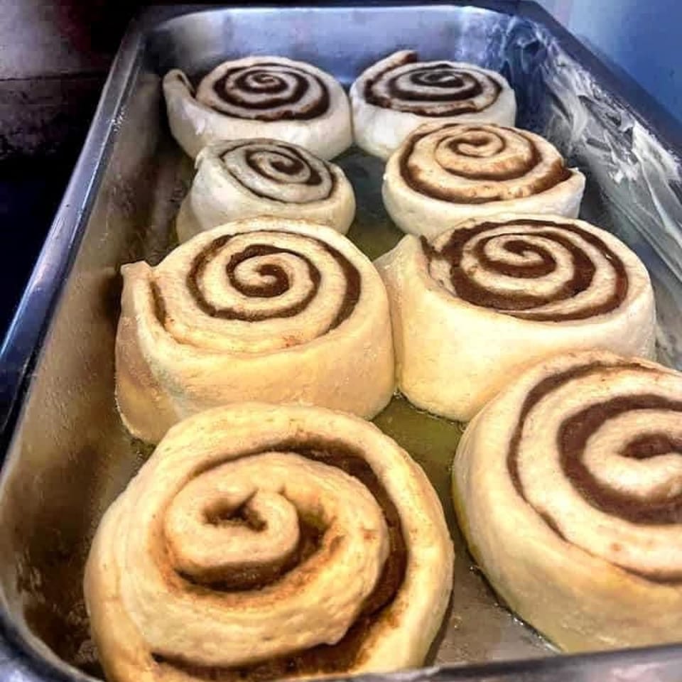 Unbaked cinnamon rolls, with visible swirls of cinnamon sugar, arranged in a metal baking pan.